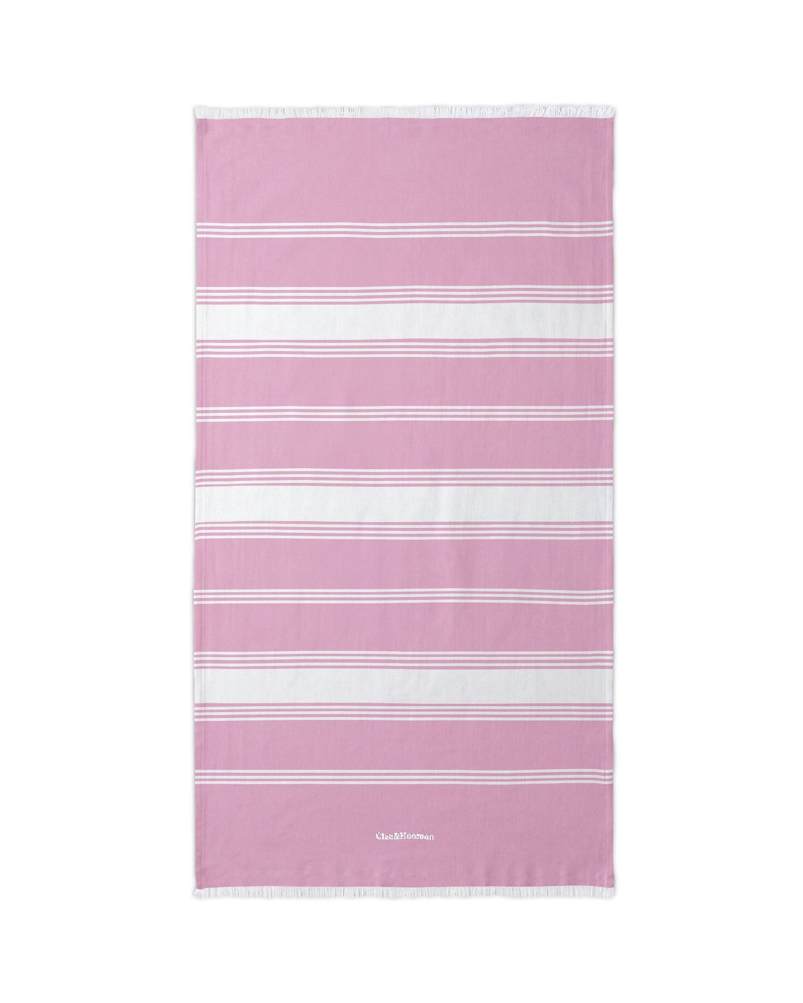 A rectangular pink beach towel with horizontal white stripes and a small white logo near the bottom, shown flat against a plain white background.