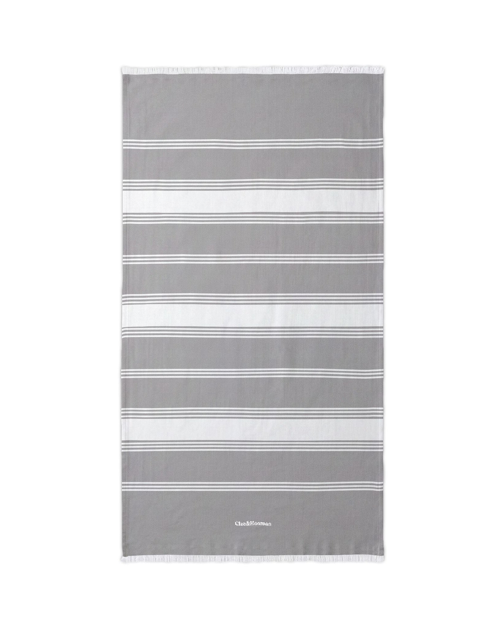 A gray and white striped beach towel with fringed edges, displayed flat against a solid white background.