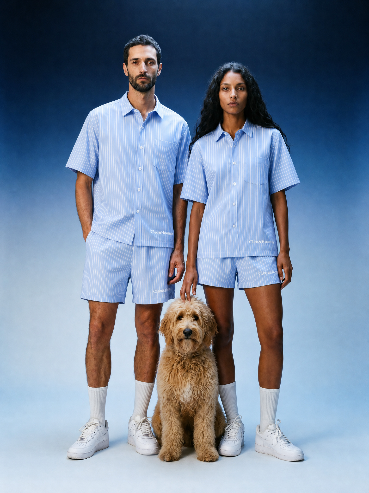 Two people in matching light blue outfits with a dog on a gradient background