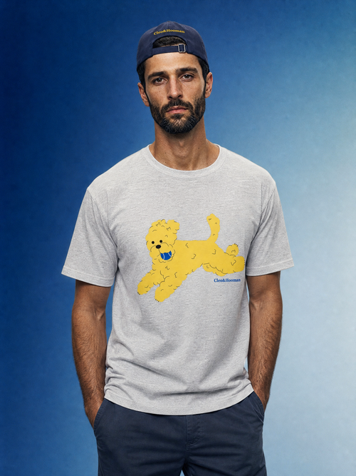 Man wearing a gray t-shirt with a yellow dog graphic and a blue cap against a blue background